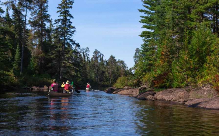 two kayaks are paddled on a calm river that flows between trees on an outward bound gap year semester